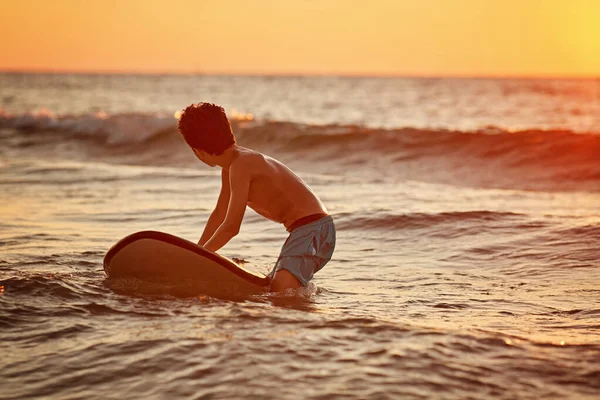 Joven surfista con tabla en la playa. Montar en el oleaje en el Océano Índico en Bali —  Fotos de Stock