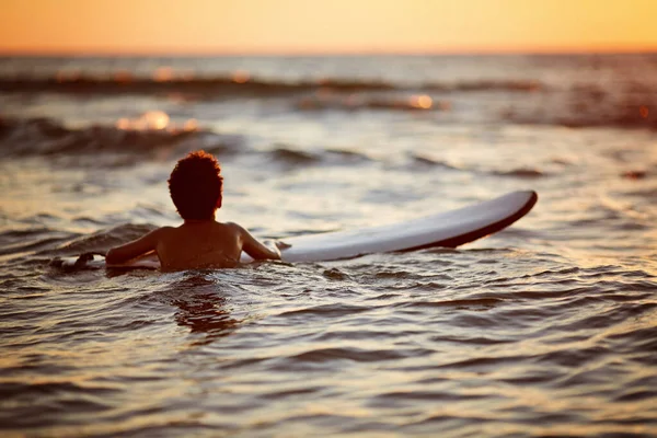 Junger Mann beim Wellenreiten bei Sonnenuntergang. Aktivität im Freien. Surfen bei Sonnenuntergang — Stockfoto