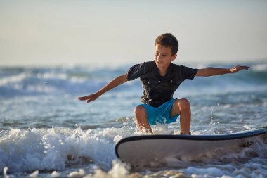 Güneşli mavi-yeşil dalganın kıvrımlarında yarışan sörfçü