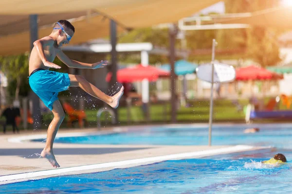 Animado adolescente menino pulando na piscina — Fotografia de Stock