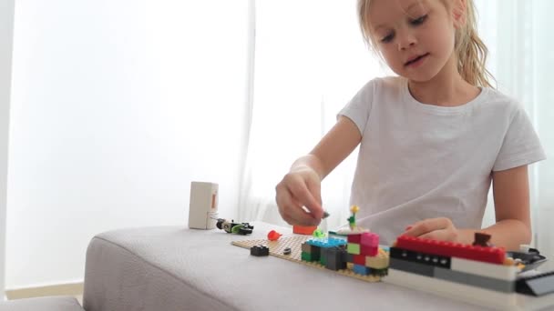 Encantador preescolar jugando con un pequeño constructor. Niña jugando con la conexión de cubos de juguete . — Vídeo de stock