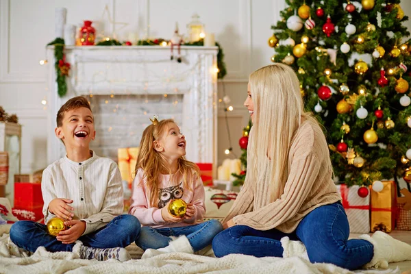 A família feliz está à espera do Ano Novo. mãe e crianças decorar a árvore de Natal — Fotografia de Stock