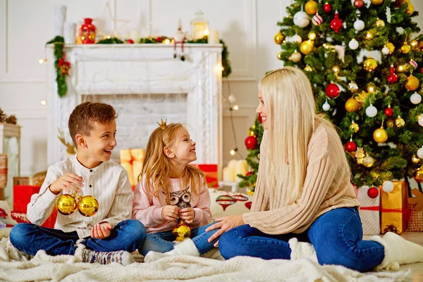 Mãe com crianças na árvore de Natal com presentes, parabenize uns aos outros Feliz Natal . — Fotografia de Stock