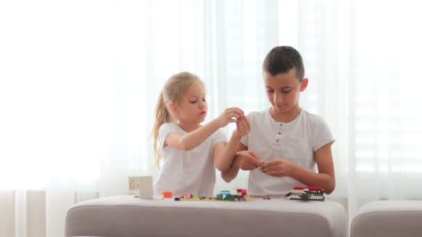 Дети пытаются собрать модель из кирпича с конструкторскими игрушками — стоковое видео