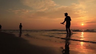 Frizbi ile plaj aydınlatmalı yaz güneş tarafından siluet oynayanlar