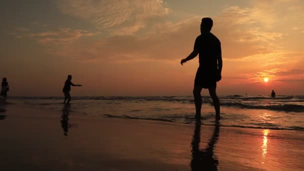 Ung pojke Silhuett fånga Frisbee plattan sommar kväll strand sport aktivitet med vänner — Stockvideo