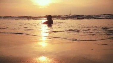 Çocuk gün batımında taş atıyor.