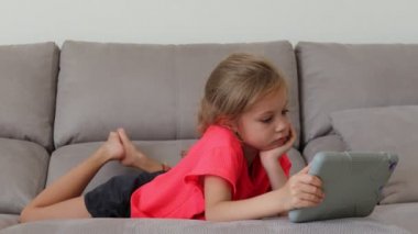 Tablet Ile eğlenceli sevimli çocuk. Küçük kız harcama boş zaman oynamak mobil oyun ve El Ile parlak ekran Hahes. Kavramı: mutlu Childfood, teknoloji, Childen Play