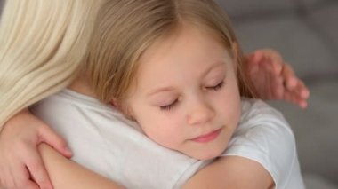 Mutlu, sevimli, sevgi dolu, evlat edinilmiş küçük kız evlatlık, koruyucu aileye sarılan, gözleri kapalı, sevimli, küçük kız çocuğu anneye sarılıyor, şefkatli anın tadını çıkarıyor.