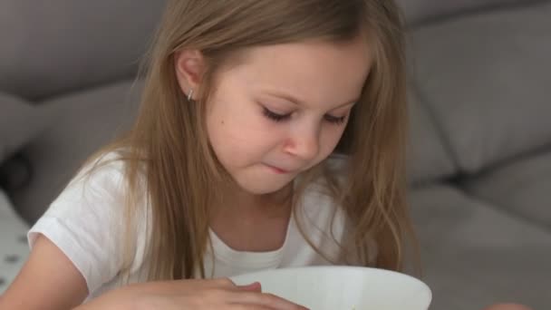 Маленька дівчинка насолоджується їжею з овочевим салатом вдома. їжа овочів дитиною робить їх здоровішими — стокове відео