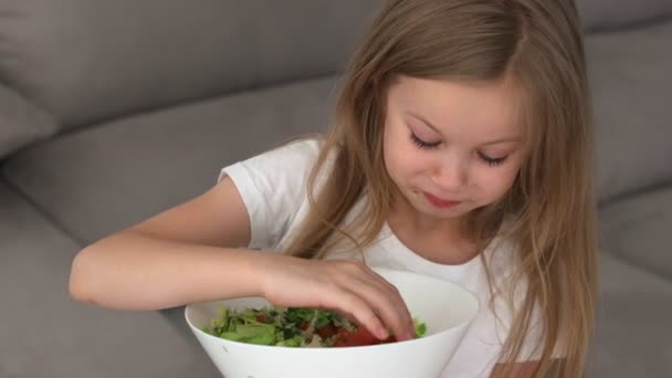 Niño come una ensalada con pepinos y tomates. Al bebé le encantan los pepinos pero no le gustan los tomates. Una ensalada saludable para niños — Vídeo de stock