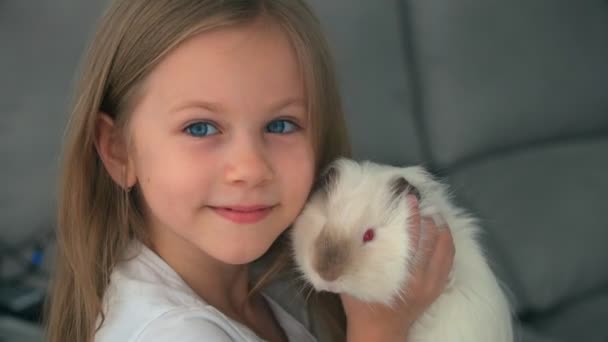 Blond meisje spelen met haar huisdier Witte cavia thuis, elkaar aanraken met hun neuzen. Dierlijke vrienden. — Stockvideo