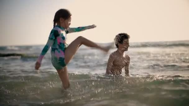 Glückliche Kinder fröhlicher kleiner Junge und Mädchen, die im Wasser spielen. Sommerferien. Sommerspaß in Zeitlupe — Stockvideo