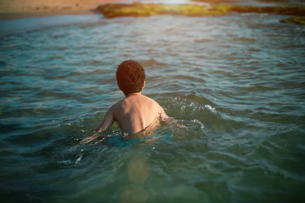 Foto de vista posterior del niño de la litera jugando en la playa en las vacaciones de verano. Niño feliz jugando en el mar —  Fotos de Stock