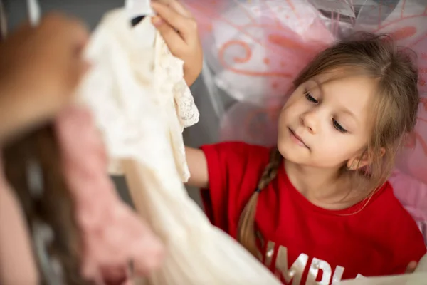 Menina pré-escolar bonito escolheu um novo vestido lindo entre um monte de roupas na loja de moda infantil — Fotografia de Stock