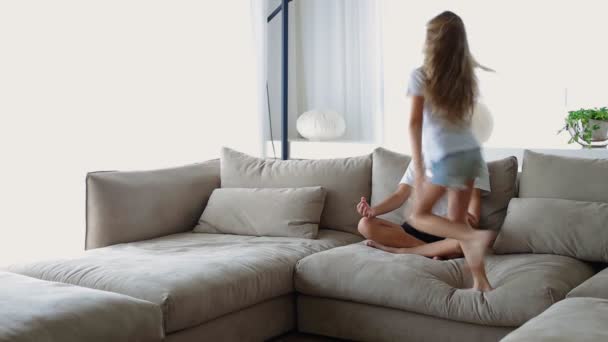 Medan aktiv galen förskola syster hoppar nära bror han sitter i Lotus position öva självbehärskning känner lugn lugn, minska stress trötthet under dagen hemma med små barn koncept — Stockvideo