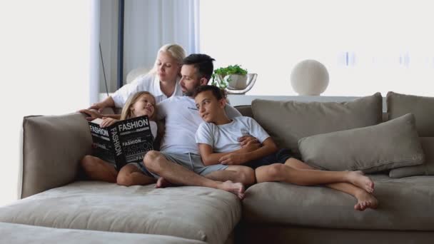 Szczęśliwa rodzina z dwójką dzieci czytających książki razem w salonie w domu. Wysokiej jakości materiał filmowy FullHD — Wideo stockowe