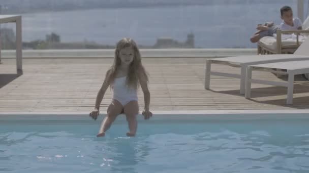 Havuzun yanında beyaz mayo giymiş küçük bir kız. — Stok video