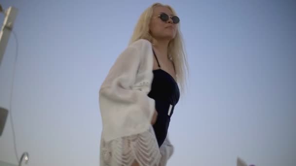 Jong sensueel en sexy vrouw met blond haar in een zwart badpak poseren en dansen — Stockvideo