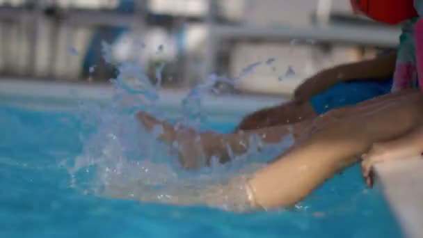 子供の足が輝く青いプールの水に飛び散っている。水泳や水を楽しむ楽しい夏の屋外活動 — ストック動画