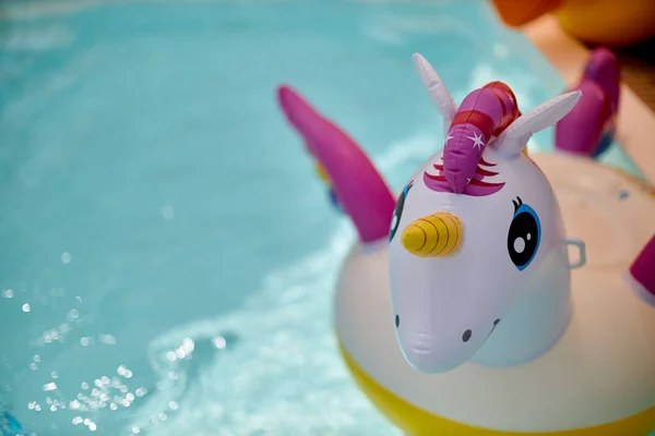 Licorne blanche colorée gonflable à la piscine. Vacances dans la piscine avec des jouets en plastique — Photo