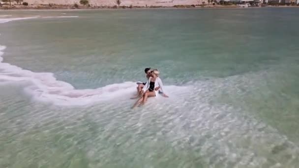 Het liefdevolle paar rust op de dode zee. De zee in Israël sterft uit en droogt op. Schieten van de drone. — Stockvideo