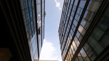 Hafif rüzgar mavi gökyüzünde büyük beyaz bulutları sürüklüyor. Yerel ofis inşaatına yansıyan panoramik pencereler zaman aşımına uğruyor.