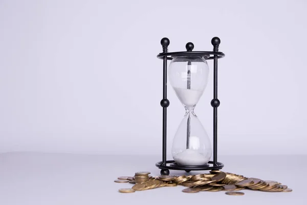 Spilled money and hourglass on a white background.