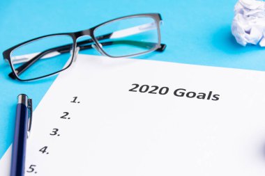 2020 için hedeflerin listesi. Kalem, buruşuk kağıt ve gözlük. Yukarıdan geldi. Boşluğu kopyala