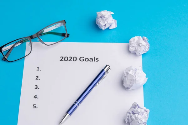 2020 için hedeflerin listesi. Kalem, buruşuk kağıt ve gözlük. Yukarıdan geldi. Boşluğu kopyala