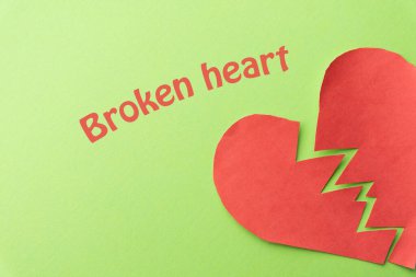 Yeşil arka planda kırık bir kalp. Yukarıdan. Boşluğu kopyala