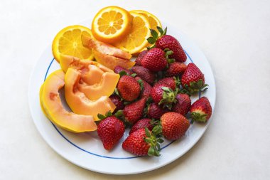 Plaka üzerinde papaya ve portakal dilimleri, üstten görünüm dilimlenmiş Olgun kırmızı çilek vardır