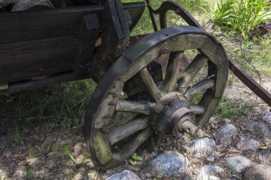 Kırsal bir sepeti metal jant ile eski bir ahşap tekerlek zemine büyüdü yakın çekim