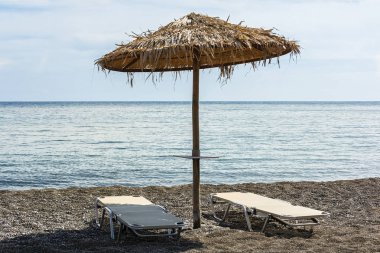 Şemsiye ve denize sıfır plaj üzerinde iki şezlong