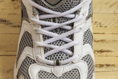 Erkek spor ayakkabı ahşap yüzeyde vardır. Beyaz dantel ile bağcıklı spor ayakkabı