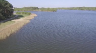Nehrin sahiline doğru yola devam edin. Genel peyzaj, sahil manzarası, yollar, ormanlar ve su. Engin su alanı.