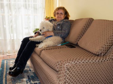 Kanepede köpeğinin yanında oturan yaşlı kadın.