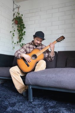 Latin adam evde oturup gitar çalıyor.