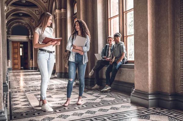 Students life!Group of beautiful students standing together and chatting on the university hall.