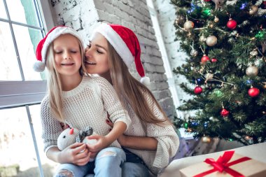 Mutlu aile anne ve çocuk kız Noel Baba şapkalı bir Noel ağacı Noel hediyesi ile yakın: