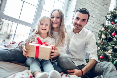 Aile bir araya getirme Noel ağacının etrafında bir hediye tutarak. Mutlu aile kavramı