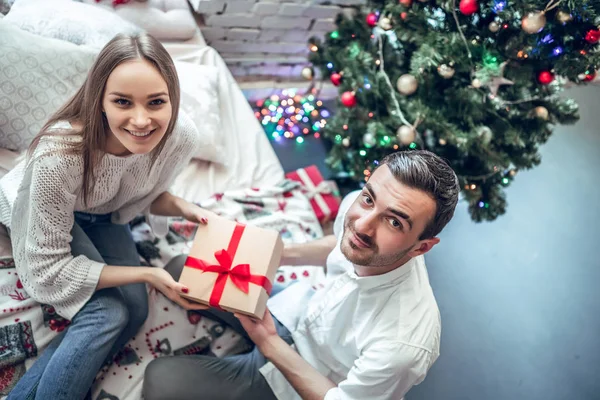 Man give present gift box woman. Christmas holiday. Happy couple sitting on bed. Top View
