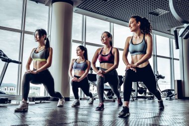 Fallouts spor salonunda yapıyor atletik vücut dört genç sportif kızla yan görünüm. Sağlam kaslar, sağlıklı vücut ve tabaklanmış deri sahip.