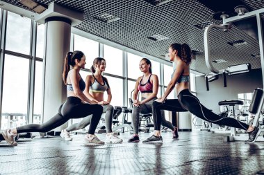 Dört atletik kadın performans gösteren düşük fallouts panoramik pencerelere ile spor salonunda. Fitness egzersizleri yapıyor.