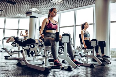 Güçlü kız atlet simülatör bacak-seyreltme egzersizleri yapıyor. Spor kavramı. Yan görünüm.