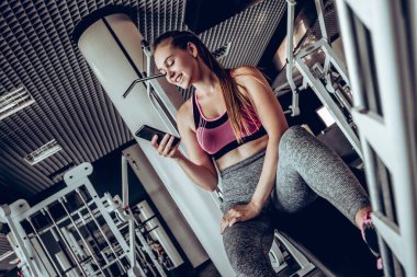 Onun smartphone kullanan genç çekici kadın spor salonunda mola.