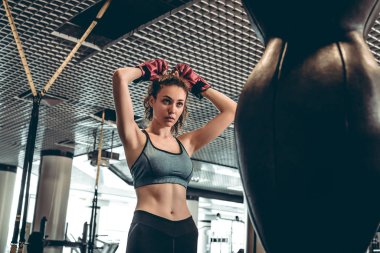 Spor kavram. Sportif kadında genç yakınındaki armut spor salonunda boks eldivenleri.