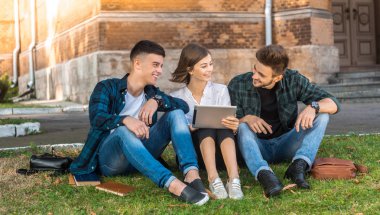 Dersten sonra hala çalışıyor. Çimde oturma ve ipad arayan öğrenciler kadeh.