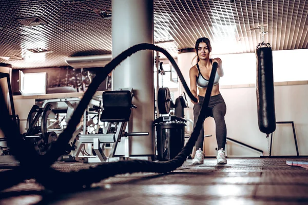 Powerful attractive muscular woman trainer do battle workout with ropes at the gym. Concept:power, strength, healthy lifestyle, sport.