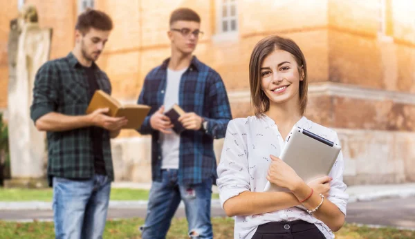 Study break with friends. Shot of a young student standing outside with friends in the background